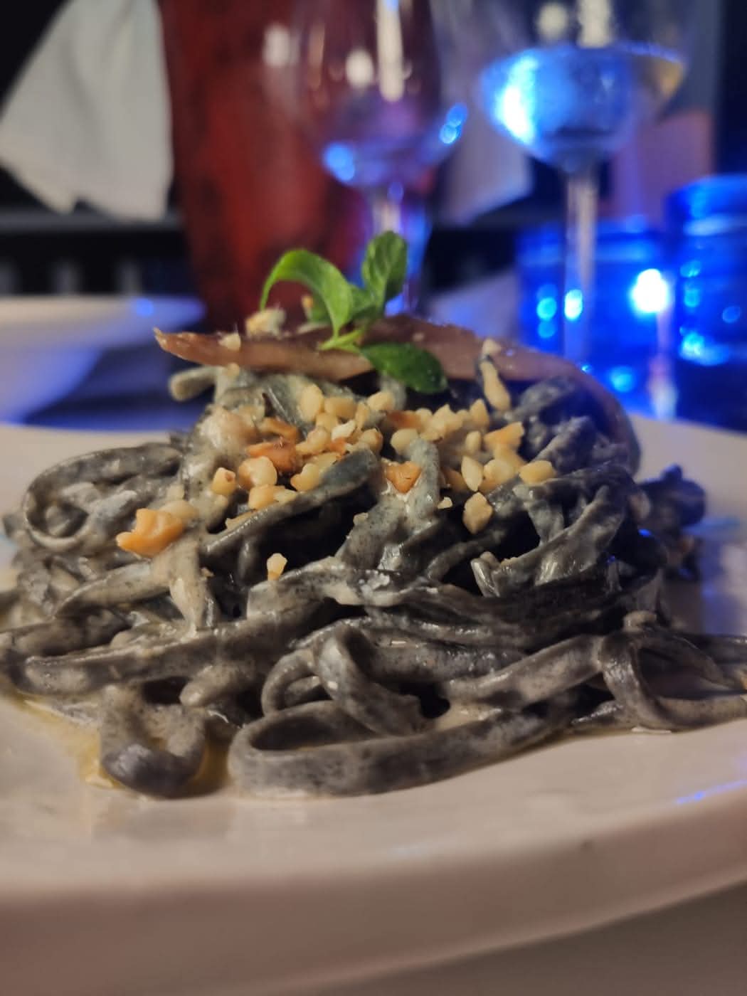 Pasta scura con salsa cremosa, briciole e una foglia di basilico