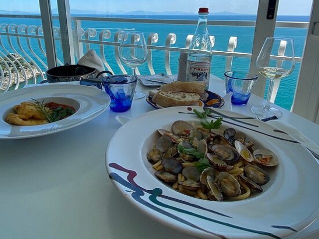 Tavolo in terrazza vista mare, con vongole e un piatto di pasta