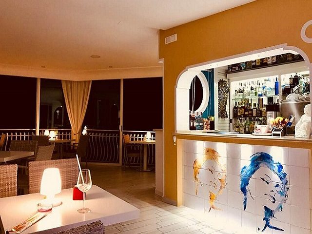 La sala di sera, con il bar e un ritratto dipinto su piastrelle