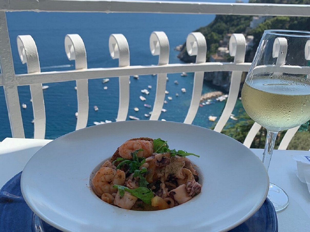 Pasta ai frutti di mare e un calice di vino bianco sulla terrazza vista mare